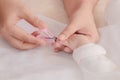 Closeup mother hand holding nail clipper cutting newborn baby nails on tiny fingers while adorable infant sleeping, keep clean Royalty Free Stock Photo