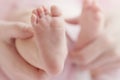 Closeup of mother hands holding cute tiny baby feet, showing baby foot. Pink Background. Horizontal Royalty Free Stock Photo