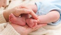 Closeup of mother holding little feet of her newborn baby lying on bed Royalty Free Stock Photo