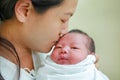 Closeup mother kissing infant baby in her arms in hospital after delivery room Royalty Free Stock Photo