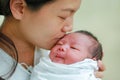 Closeup mother kissing infant baby in her arms in hospital after delivery room Royalty Free Stock Photo