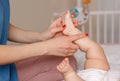 Mother parent doing heel toe foot massage and physical exercises to newborn baby