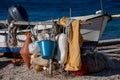 Closeup of a motor boat stern on a sandy beach with sailing rigging, buckets and buoys