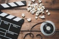 Closeup of movie camera with film reel clapper board and popcorn on wood. Royalty Free Stock Photo