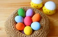 Closeup Multi-colored Easter Eggs in a Basket with Blurry Two Adorable Chicks in Background