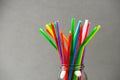 Closeup of multi colored plastic straws in a jar in front of grey background. Royalty Free Stock Photo