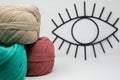 Closeup of multicolored knitting wool balls and an open eye line ornament on the wall Royalty Free Stock Photo