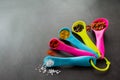 Closeup multicolored measuring spoons with spices: chili flakes, a mix of pepper peas, curry, paprika and coarse sea salt. Black