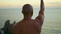 Closeup muscular man stretching arms at ocean sunset view. Athlete doing hand