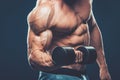 Closeup of a muscular young man lifting dumbbells weights on dar Royalty Free Stock Photo