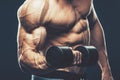 Closeup of a muscular young man lifting dumbbells weights on dar Royalty Free Stock Photo