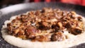 Closeup of mushroom and onion gravy on top of dosa steaming on a nonstick pan