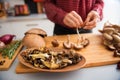 Closeup of mushrooms in a dish with woman stringing mushrooms