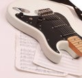 Closeup of music sheets and black-and-white electric guitar.iso Royalty Free Stock Photo
