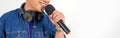 Closeup musician`s hand holding microphone. Young asian man singing on white background Royalty Free Stock Photo