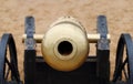 Closeup of muzzle of old metal cannon with wheel on sand Royalty Free Stock Photo