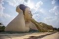 Closeup of the Mya Tha Lyaung reclining Buddha against a cloudy sky with a bright sun