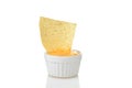 Closeup nacho chip dipped in small bowl of spicy cheese