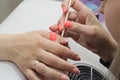 Closeup nail service mater assists cuticle removal procedure with wooden handle in salon