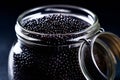 Closeup of natural black caviar in jar on black background, texture of luxury fresh sturgeon caviar macro photo.