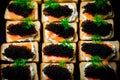 Closeup of natural black caviar served on crackers on black background, texture of fresh sturgeon caviar macro photo.