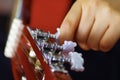 Closeup neck of beautiful acoustic guitar being tuned by woman sitting down, musician concept