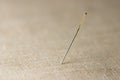 Closeup of needle on linen cloth background