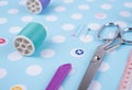 Closeup needles, thread spool, scissors, button on blue wooden