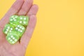 Closeup of neon green dice on a person's palm isolated on a yellow background