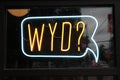 Closeup of a neon sign on the glass with WYD text