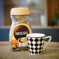 Closeup of Nescafe instant coffee Crema in a glass jar and a glass mug standing on a table