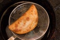 Closeup of newly cooked empanada scooped out from a pot and drained Royalty Free Stock Photo