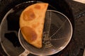 Closeup of newly cooked empanada scooped out from a pot and drained Royalty Free Stock Photo