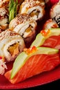 Closeup of nigiri sushi with salmon, avocado, red caviar and unagi rolls with eel, cream cheese and orange on red plate Royalty Free Stock Photo