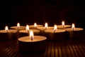 Closeup of nine candles in the dark on a wooden table