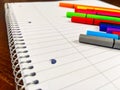 Closeup of notebook spiral and colorful pens laying on an empty white notebook with lines, used for note taking in school, while Royalty Free Stock Photo