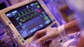 A closeup of a nurses hands deftly administering medication to a patient while simultaneously checking their vital signs