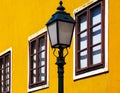 Closeup of retro style street lantern lamp on cast iron post. colorful yellow stucco exterior wall background Royalty Free Stock Photo