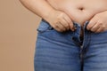 Closeup of obese woman with overweighted stomach zipping up jeans. Sudden weight gain. Visceral fat. Body positive