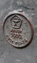 Grunge metal texture with round relief label of Soviet quality mark closeup