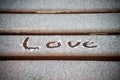 The word `love` writed in the freeze on wooden bench in the street Royalty Free Stock Photo