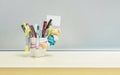 Closeup office equipment and color pen in desk tidy cup for pen on blurred wooden desk and frosted glass wall textured background