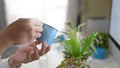 Closeup office man is watering the potted plant at the white desk.