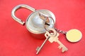Closeup the old brass metal door lock with key and key ring over out of focus red background Royalty Free Stock Photo