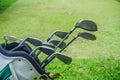 Closeup old golf bags on green. Set of golf clubs over green field background Royalty Free Stock Photo