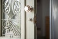 Closeup of old home white wooden door with stained glass, metal lattice. Open vintage entrance doorway, round handle, broken lock Royalty Free Stock Photo