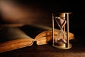 Old hourglass and ancient book with open pages Royalty Free Stock Photo