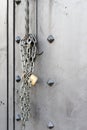 Closeup of old Iron door with closed padlock on a chain. A chain of silver color with closed padlock on an old gate.