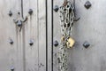 Closeup of old Iron door with closed padlock on a chain. A chain of silver color with closed padlock on an old gate. Royalty Free Stock Photo