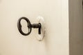 Closeup of an old keyhole with key on a wooden white door. Old key in keyhole, macro shot. Key to knowledge. Concept and Royalty Free Stock Photo